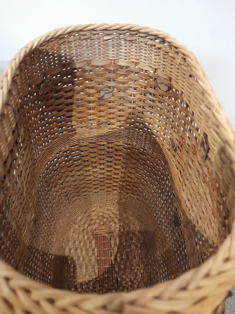 May include: A woven wicker basket with a round opening. The basket is made of natural brown wicker and has a smooth, even weave.