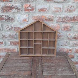 May include: A wooden display case with a house-shaped frame and 20 individual compartments. The case is brown and has a rustic appearance.