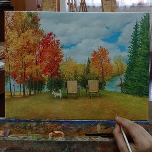 Puede incluir: Una pintura de un paisaje oto&ntilde;al con dos sillas y un perro blanco. Los &aacute;rboles est&aacute;n en tonos de rojo, naranja y amarillo. El cielo es azul con nubes blancas. Las sillas son de madera y tienen cojines blancos. El perro corre hacia el lado derecho de la pintura.