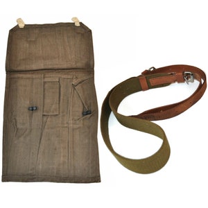Könnte beinhalten: Eine olivgrüne Canvas-Tasche mit Klappenverschluss und zwei kleinen Taschen, zusammen mit einem passenden grünen Canvas-Gurt mit braunen Lederakzenten. Die Tasche hat zwei schwarze Verschlüsse.