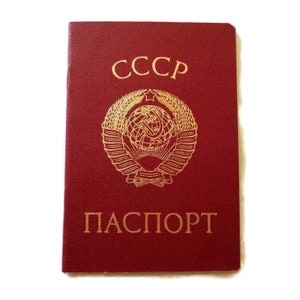 May include: A red passport with gold lettering and a gold emblem. The text "CCCP" is at the top, and "ПАСПОРТ" is at the bottom. The emblem features a globe, wheat, a star, and other elements.