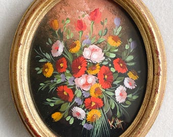 May include: An oval-shaped wall hanging featuring a floral oil painting in a distressed gold frame. The artwork depicts a vibrant bouquet of red, orange, yellow, and pink flowers with green stems against a dark background. The signature K.H. is visible.