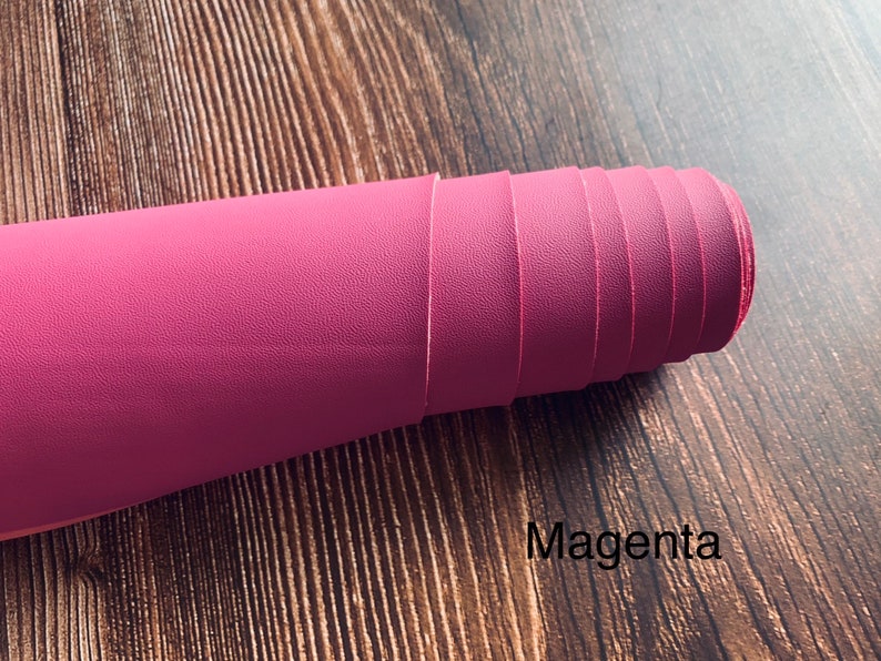 Puede incluir: Un rollo de tela de imitaci&oacute;n de cuero de color magenta. La tela tiene una superficie texturizada.