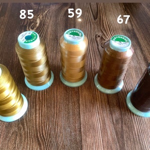 May include: Five spools of thread in various shades of brown and gold. The spools are labeled with numbers: 82, 85, 59, 67, and 116.