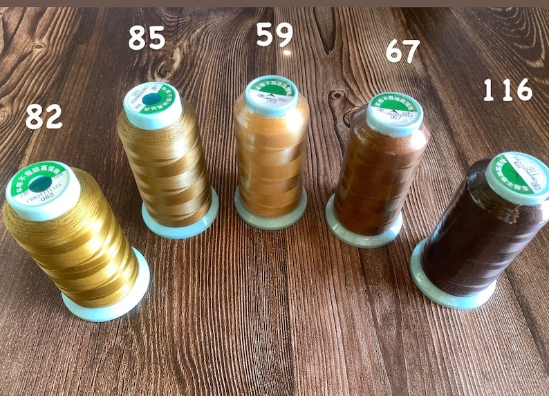 May include: Five spools of thread in various shades of brown and gold. The spools are labeled with numbers: 82, 85, 59, 67, and 116.