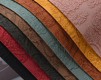 May include: A close-up of eight fabric swatches in various colours, including pink, yellow, orange, brown, teal, grey, black, and red. The fabric has a textured, embossed design.