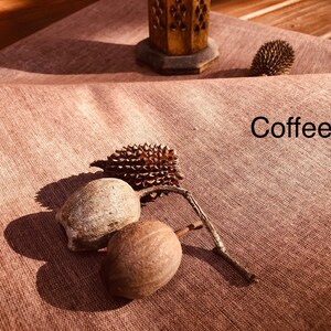 K&ouml;nnte beinhalten: Drei braune Samenkapseln mit einer stacheligen braunen Samenkapsel auf einer braunen Stoffoberfl&auml;che. Der Text "Coffee" ist auf dem Stoff geschrieben.
