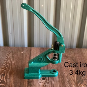 Op de afbeelding: Een groene knopenpers van gietijzer met een hendel. De pers weegt 3,4 kg.