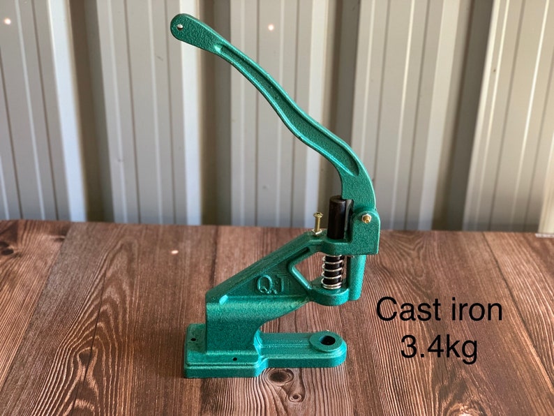 Op de afbeelding: Een groene knopenpers van gietijzer met een hendel. De pers weegt 3,4 kg.