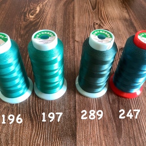 May include: Four spools of green thread with white labels. The labels have Chinese characters and the numbers 196, 197, 289, and 247.
