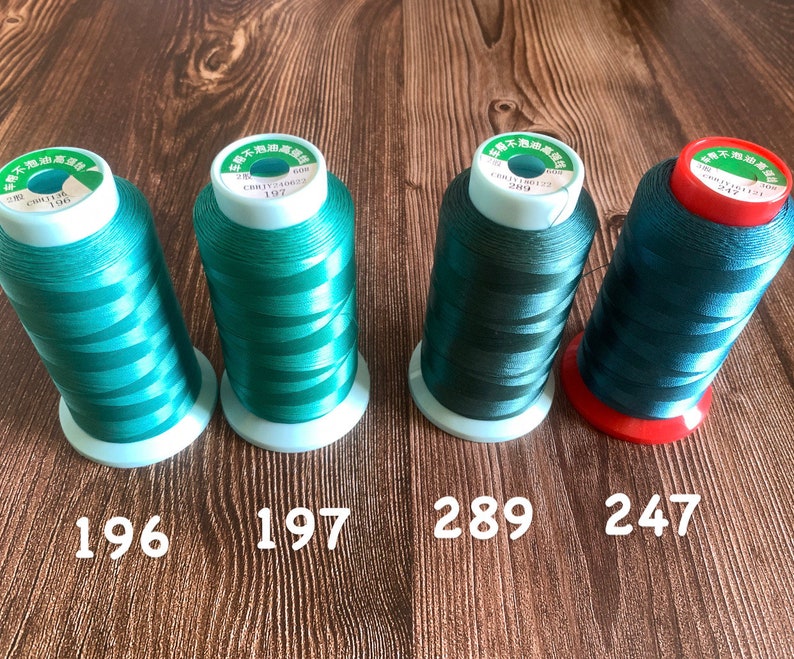 May include: Four spools of green thread with white labels. The labels have Chinese characters and the numbers 196, 197, 289, and 247.