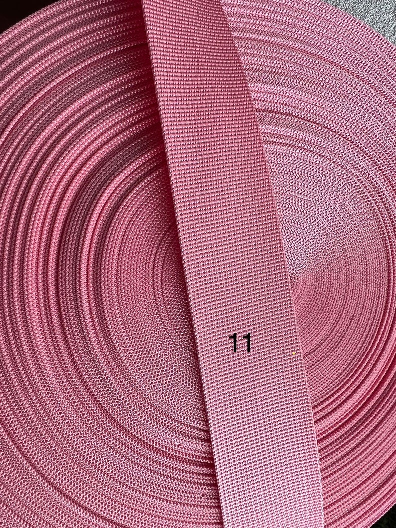 May include: A roll of pink webbing with a close-up of the webbing showing the texture. The number "11" is printed on the webbing.