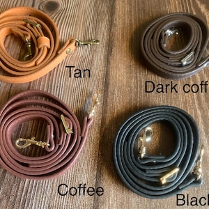 Puede incluir: Cuatro correas de cuero en diferentes colores: marrón claro, café, café oscuro y negro. Cada correa tiene herrajes dorados y está enrollada.