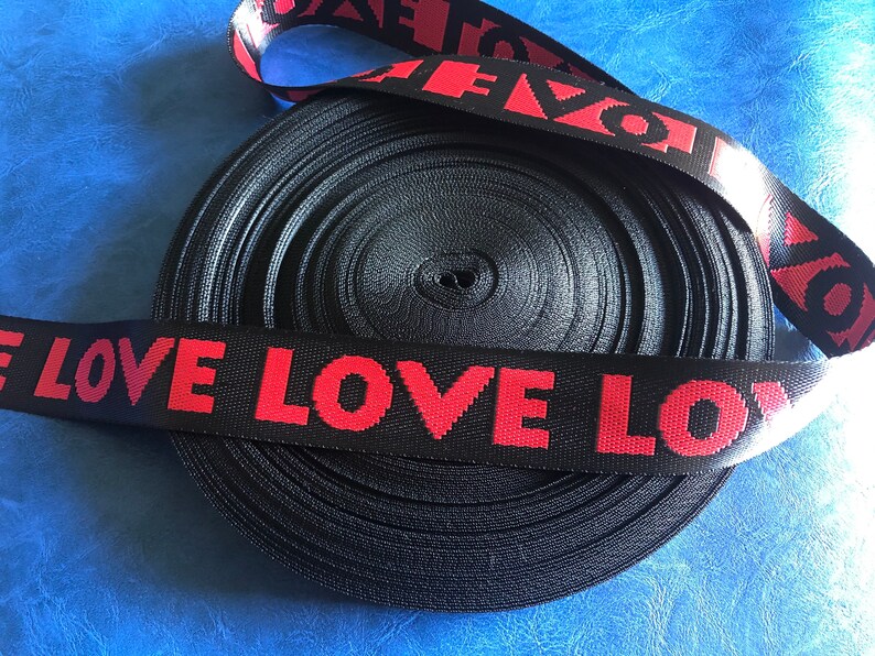 May include: Black and red elastic ribbon with the word "LOVE" repeated in red lettering.