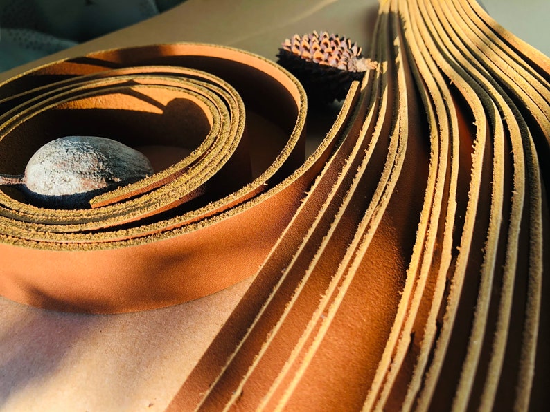 K&ouml;nnte beinhalten: Nahaufnahme einer Rolle brauner Lederriemen. Die Riemen sind spiralf&ouml;rmig angeordnet und haben eine raue, unfertige Kante.