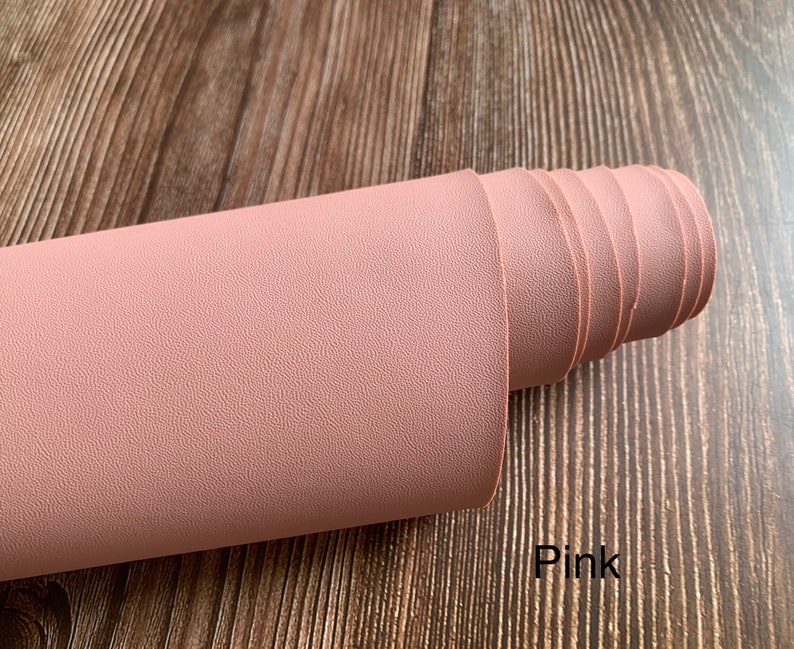 Puede incluir: Un rollo de tela de imitaci&oacute;n de cuero rosa con una superficie texturizada. Rosa.