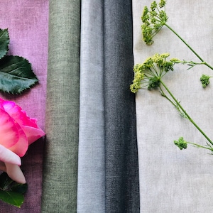 May include: Four fabric swatches in different colours and textures. The swatches are arranged horizontally, with a pink rose and green leaves on the left and green sprigs of flowers on the right.