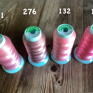May include: Four spools of pink thread with white stripes. Each spool has a green label with Chinese text and a number: 171, 276, 132, and 182.