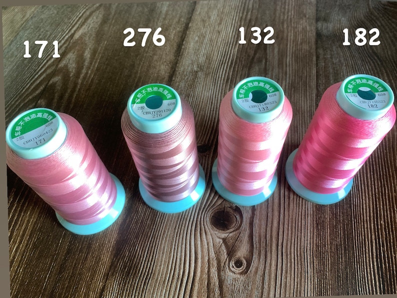 May include: Four spools of pink thread with white stripes. Each spool has a green label with Chinese text and a number: 171, 276, 132, and 182.