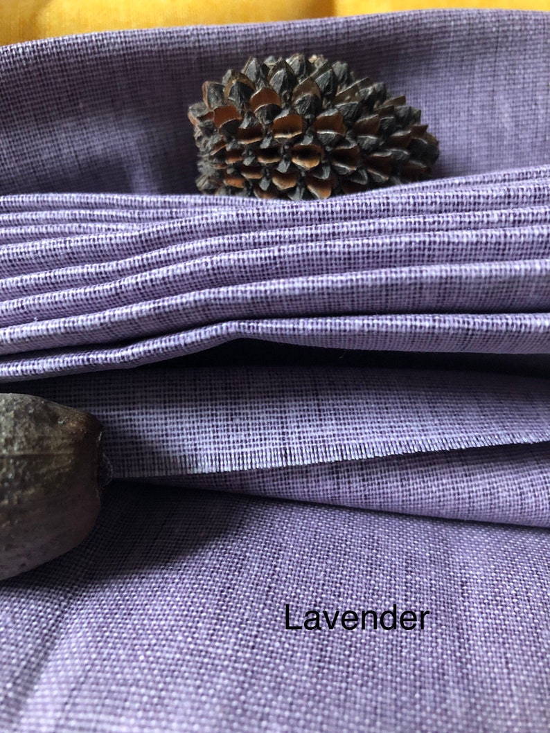 K&ouml;nnte beinhalten: Nahaufnahme eines lavendelfarbenen Stoffes mit einer strukturierten Webart. Der Stoff ist gefaltet und das Wort "Lavender" ist in der unteren rechten Ecke aufgedruckt.