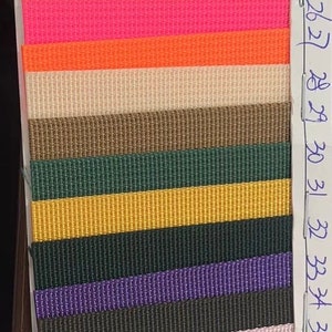 May include: A sample card of 24 different colors of woven webbing. The colors range from light gray to dark purple. The card is labeled with numbers 18 through 41.