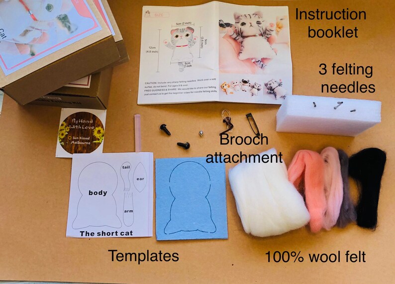 May include: A felting kit for making a short cat brooch. The kit includes white, pink, gray, and black wool felt, three felting needles, a foam pad, a brooch attachment, and templates for the body, ears, tail, and arm. The kit also includes instructions.