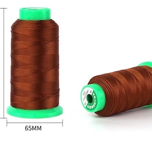 May include: Two spools of brown thread with green plastic caps. The spools are 110mm tall and 65mm wide.