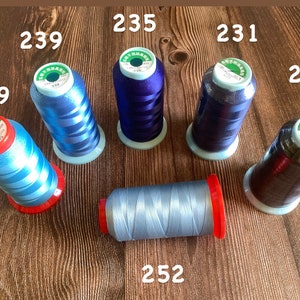 May include: Six spools of thread in various shades of blue and black. The spools are labeled with numbers: 239, 235, 231, 225, 249, and 252.