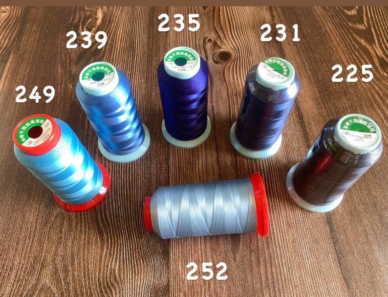 May include: Six spools of thread in various shades of blue and black. The spools are labeled with numbers: 239, 235, 231, 225, 249, and 252.