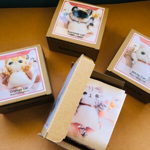 May include: Four boxes containing wool felting kits for making different colored cats. The boxes are brown with white labels and feature images of the finished felted cats. The labels include the text "Orange cat", "Siamese cat", "White Cat", and "Wool Felting Kits".