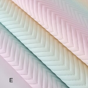 May include: Two pieces of fabric with a chevron pattern in a gradient of pastel colors, including pink, blue, and yellow. The fabric has a quilted texture with small dots.
