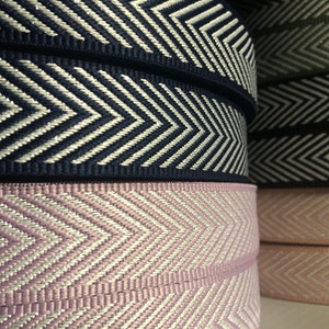 Puede incluir: Primer plano de tres rollos de cinta de chevron blanco y azul marino, una cinta de chevron rosa y blanco y una cinta de chevron rosa.