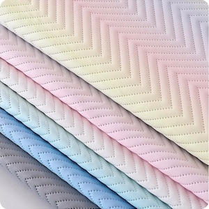 May include: Five pieces of fabric with a chevron pattern in shades of pink, blue, and gray. The fabric is quilted with small dots.