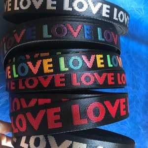 May include: A stack of black webbing with the word "LOVE" printed in various colors, including white, red, blue, green, and yellow.