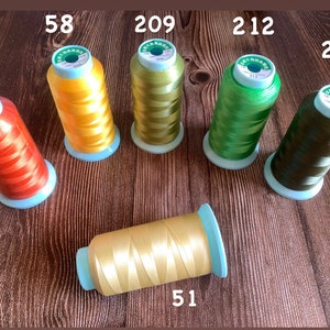 May include: Six spools of embroidery thread in various colors, including orange, yellow, green, and brown. The spools are labeled with numbers: 72, 58, 209, 212, 254, and 51.