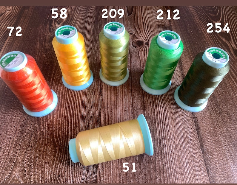 May include: Six spools of embroidery thread in various colors, including orange, yellow, green, and brown. The spools are labeled with numbers: 72, 58, 209, 212, 254, and 51.