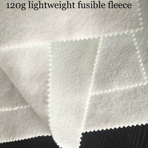 K&ouml;nnte beinhalten: Wei&szlig;er, 120 g leichter, verschwei&szlig;barer Fleece-Stoff. Der Stoff hat auf der einen Seite eine gepunktete Struktur und auf der anderen Seite eine glatte Struktur.