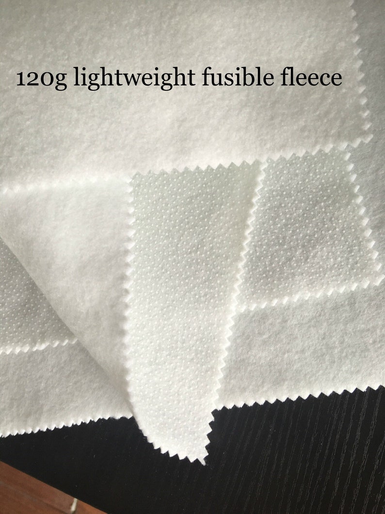 K&ouml;nnte beinhalten: Wei&szlig;er, 120 g leichter, verschwei&szlig;barer Fleece-Stoff. Der Stoff hat auf der einen Seite eine gepunktete Struktur und auf der anderen Seite eine glatte Struktur.