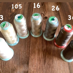 May include: Eight spools of thread in various colors, including white, beige, brown, and black. The spools are labeled with numbers 1, 2, 3, 16, 26, 36, 105, and 207.