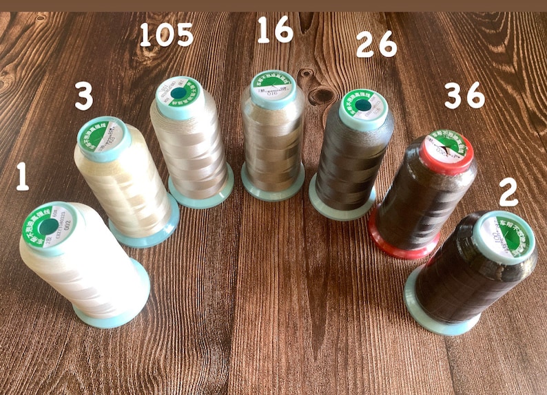 May include: Eight spools of thread in various colors, including white, beige, brown, and black. The spools are labeled with numbers 1, 2, 3, 16, 26, 36, 105, and 207.