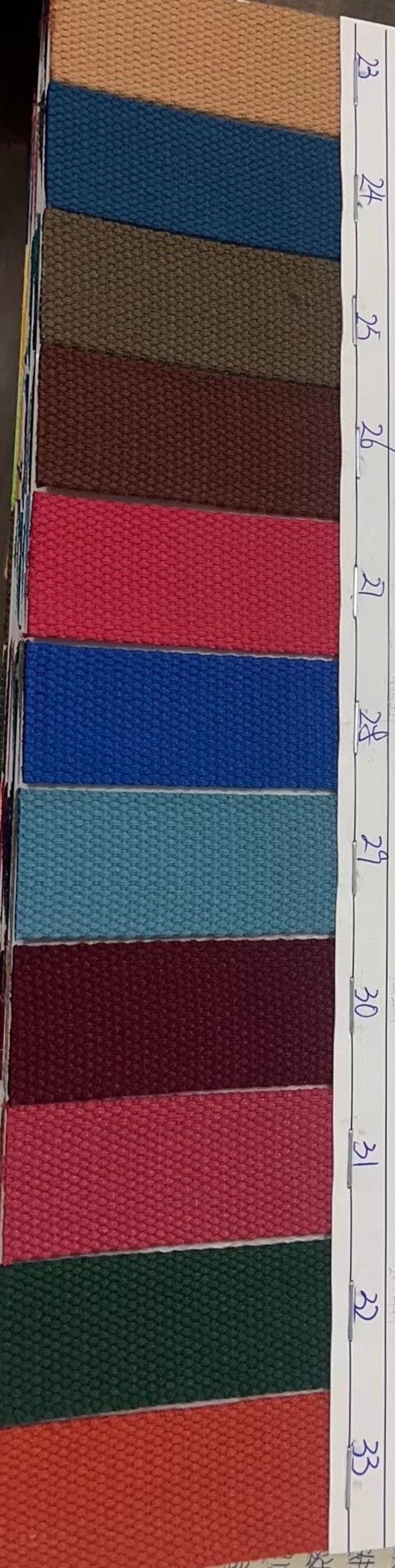 May include: A sample card with 12 fabric swatches, numbered 23 through 34. The swatches are in various colors, including beige, blue, green, brown, red, and teal.