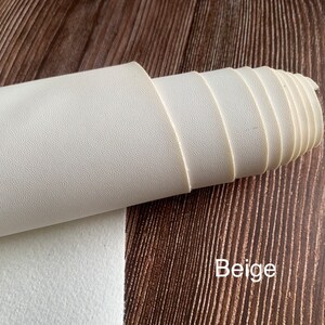 Puede incluir: Un rollo de tela de imitaci&oacute;n de cuero beige con una superficie texturizada.
