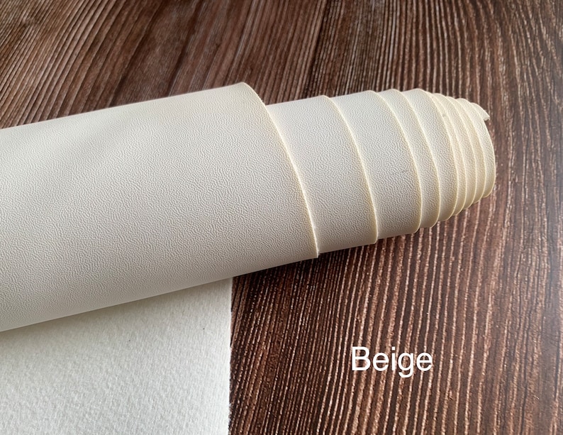 Puede incluir: Un rollo de tela de imitaci&oacute;n de cuero beige con una superficie texturizada.