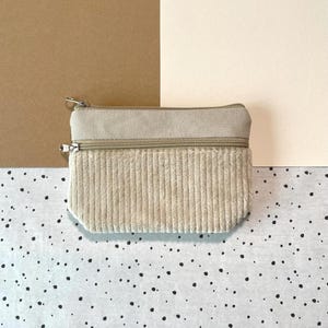 Kleiner Geldbeutel aus beigefarbenen Cord und Canvas Stoff. Die Geldbörse hat zwei Fächer mit Reißverschluss. Ein größeres Fach für Bargeld und ein kleineres Fach für viele Karten.