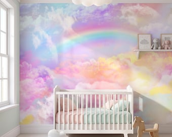 Puede incluir: Una cuna blanca con ropa de cama a rayas se sitúa frente a un mural de pared con un arcoíris y nubes pastel. Un cojín con forma de nube y un caballito balancín de madera están en el suelo. Un estante sostiene dos cuadros y dos peluches.