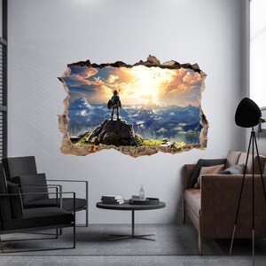 Puede incluir: Un adhesivo de pared con un efecto 3D de un agujero en la pared que revela un paisaje. Una figura se encuentra sobre un afloramiento rocoso con vistas a una vasta cordillera bajo un cielo dorado al atardecer con nubes y aves.