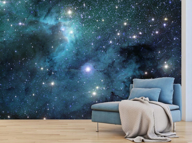 May include: A wall mural depicting a vibrant nebula in shades of teal and blue, speckled with numerous bright stars. A teal sofa with pillows and a beige blanket is placed in front of the mural, creating a cozy atmosphere.