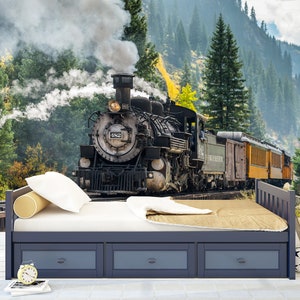 May include: A dark blue wooden bed frame with three storage drawers underneath, featuring a white mattress, a white pillow, a cylindrical yellow bolster, and a tan blanket. The bed is positioned against a wall mural of a steam locomotive.