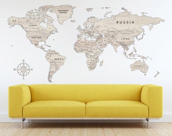 May include: A wooden world map wall decor with country names and borders, mounted on a white wall. A compass rose is to the left of the map. A yellow sofa sits below the map.