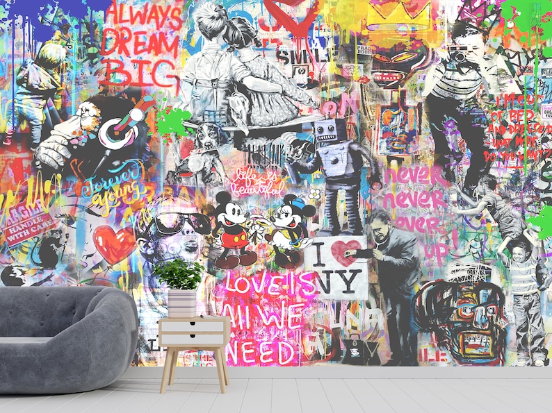 Op de afbeelding: Een muurschildering met een levendige collage van street art, inclusief graffititeksten zoals ALWAYS DREAM BIG, stripfiguren zoals Mickey en Minnie Mouse, een robot en diverse abstracte verfspatten in felle neon- en primaire kleuren.